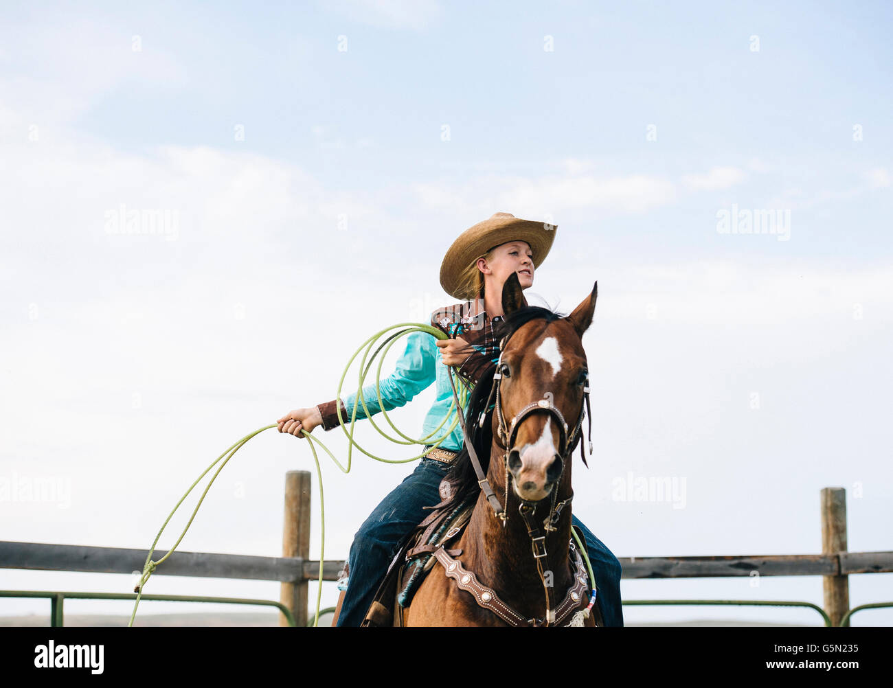 Caucasian cowgirl throwing lasso on horseback Stock Photo