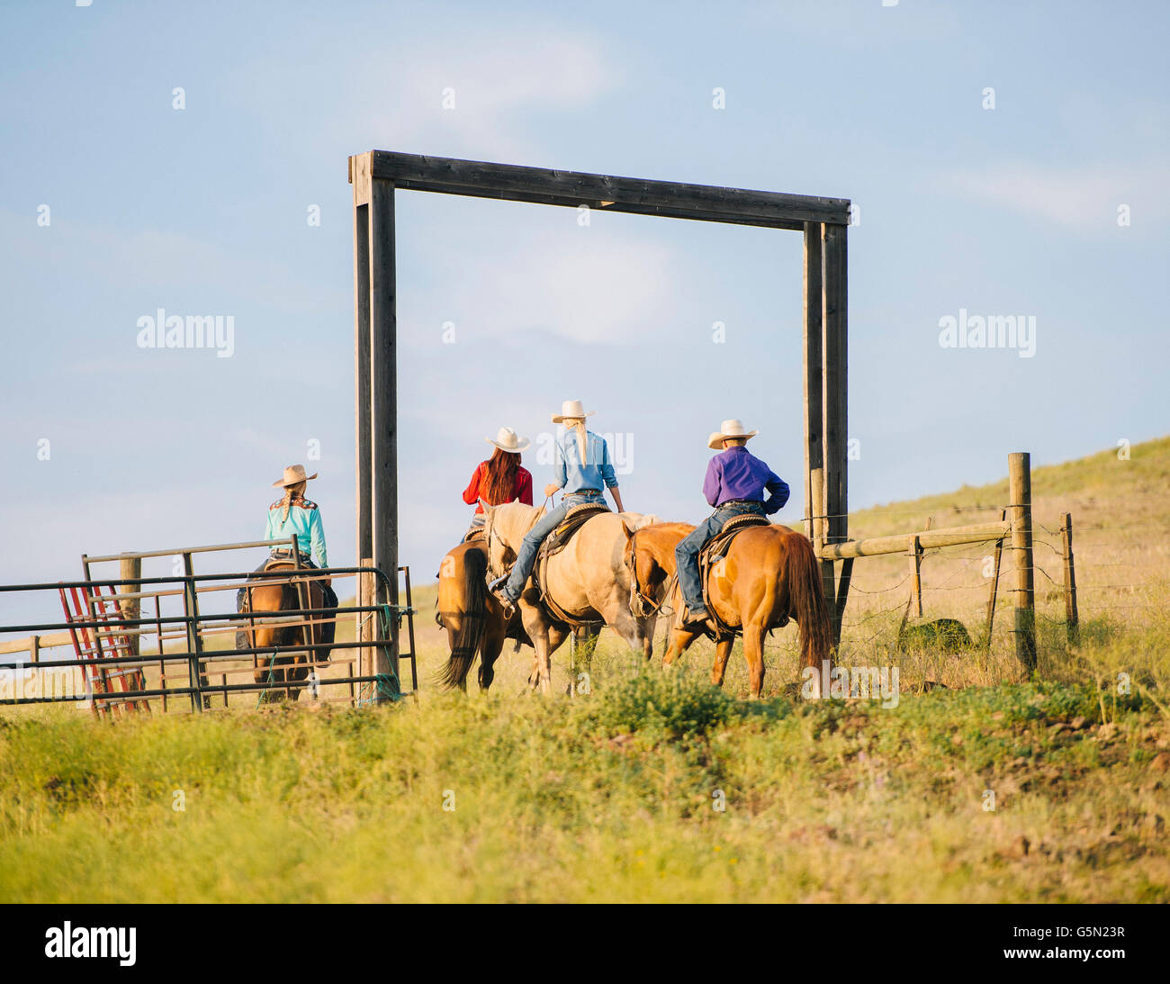 Cowboy and cowgirls riding horseback on ranch Stock Photo