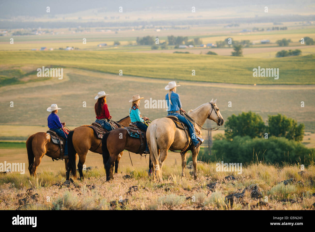 Cowboy and cowgirls on horseback admiring rural landscape Stock Photo