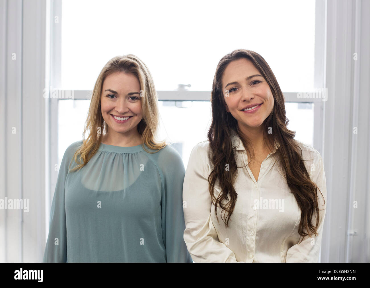 Caucasian businesswomen smiling near window Stock Photo