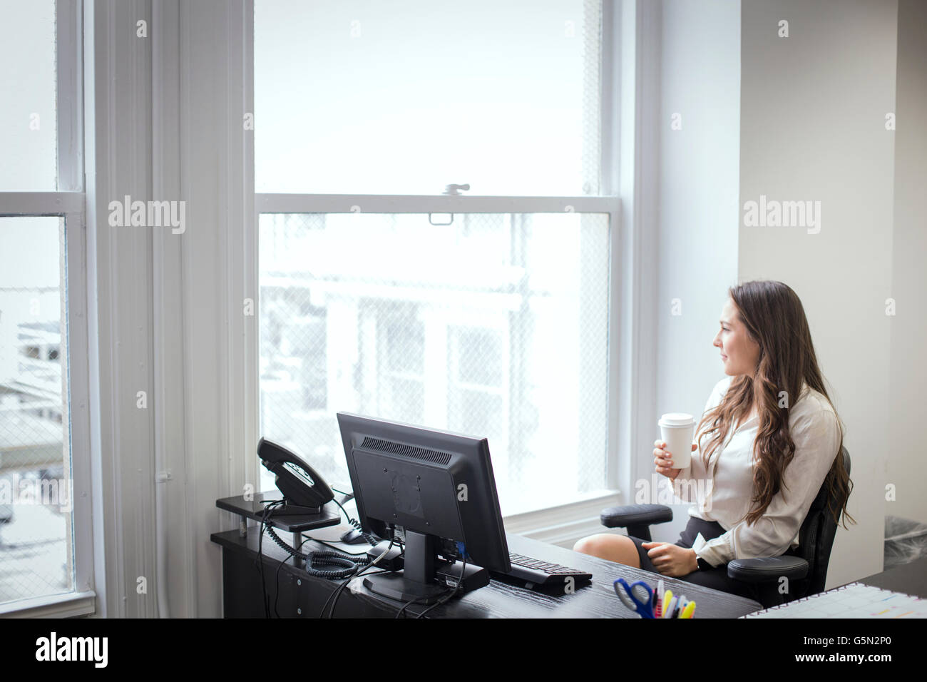 Caucasian businesswoman looking out office window Stock Photo