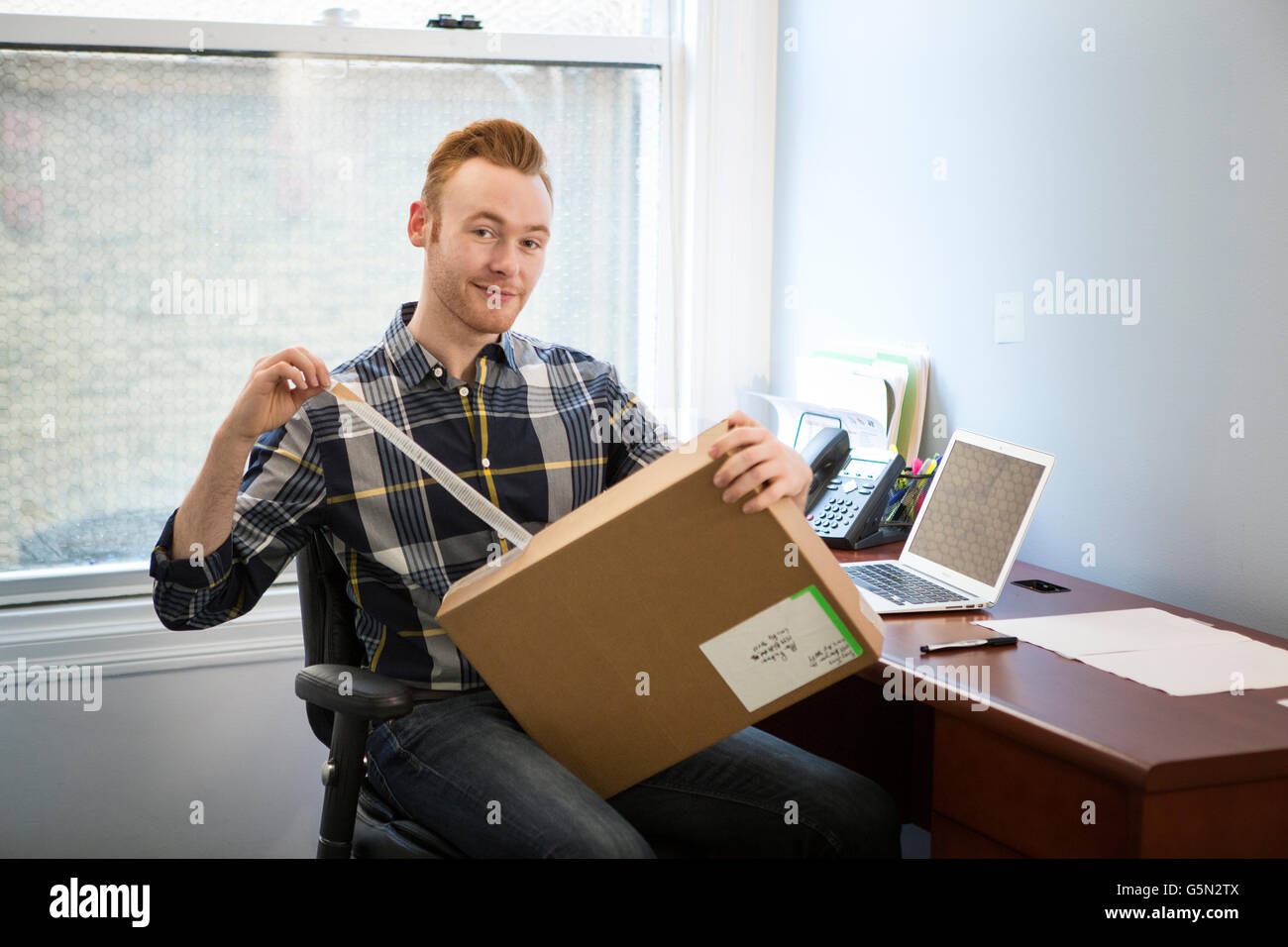 Caucasian businessman opening package in office Stock Photo