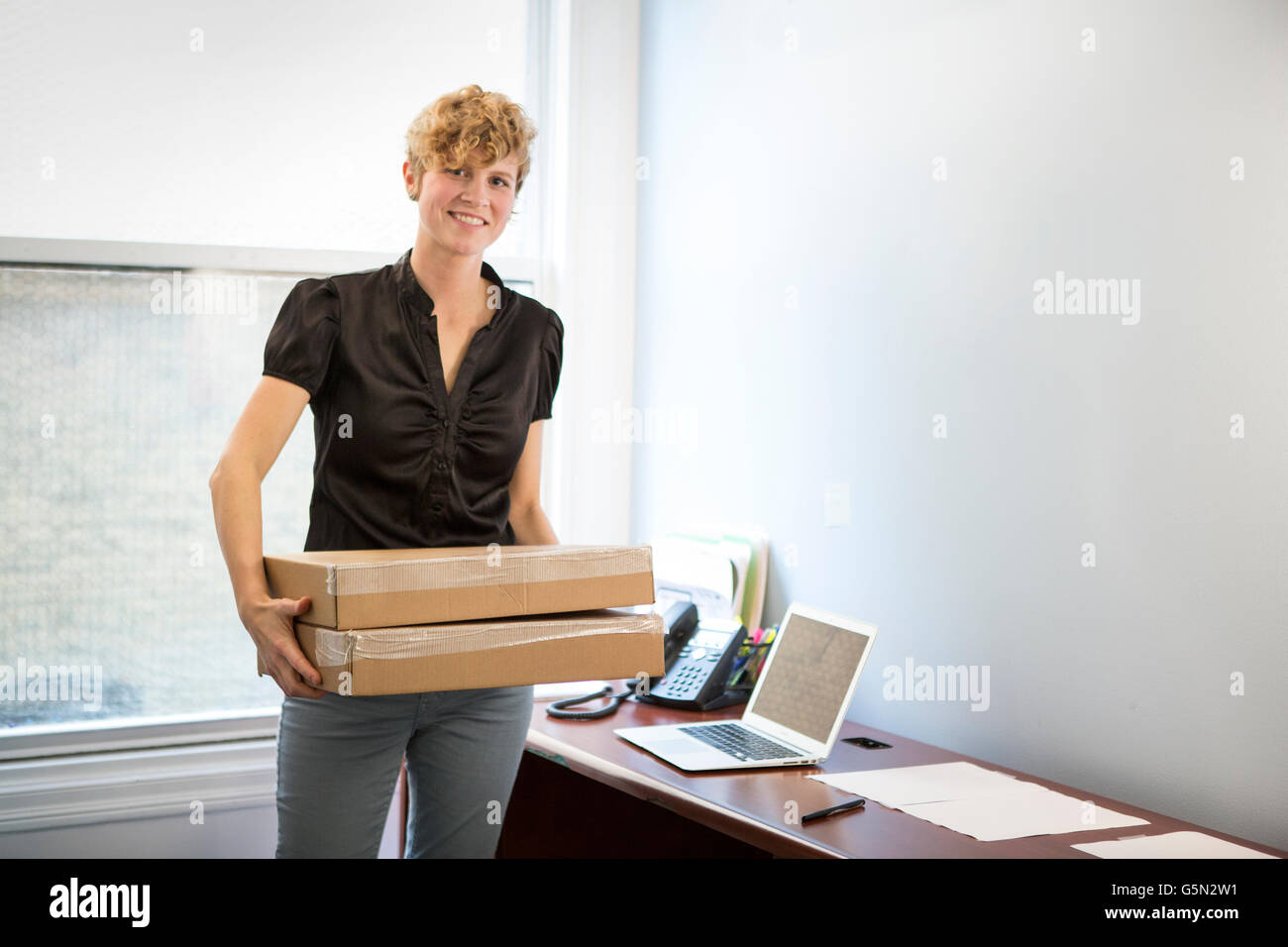 Caucasian businesswoman holding package in office Stock Photo