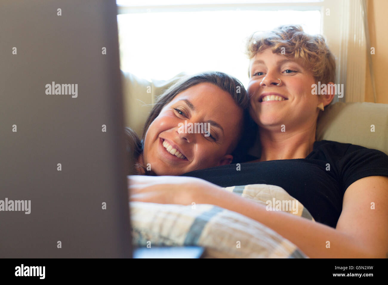 Caucasian lesbian couple cuddling in bed Stock Photo