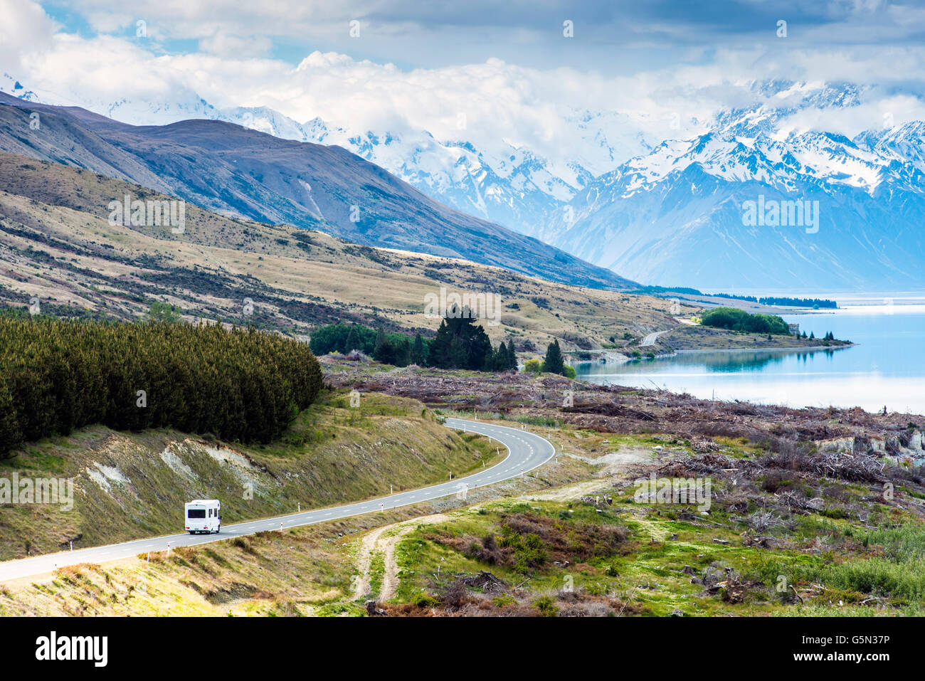 RV driving near mountains and lake in remote landscape Stock Photo