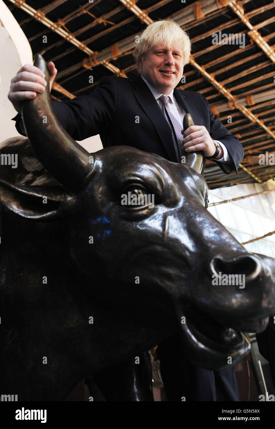 London mayor Boris Johnson poses with a cast of a bronze bull, the symbol of the Bombay Stock Exchange after officially opening the day's trading in Mumbai, as part of a week long tour of India where he is trying to persuade Indian businesses to invest in London. Stock Photo