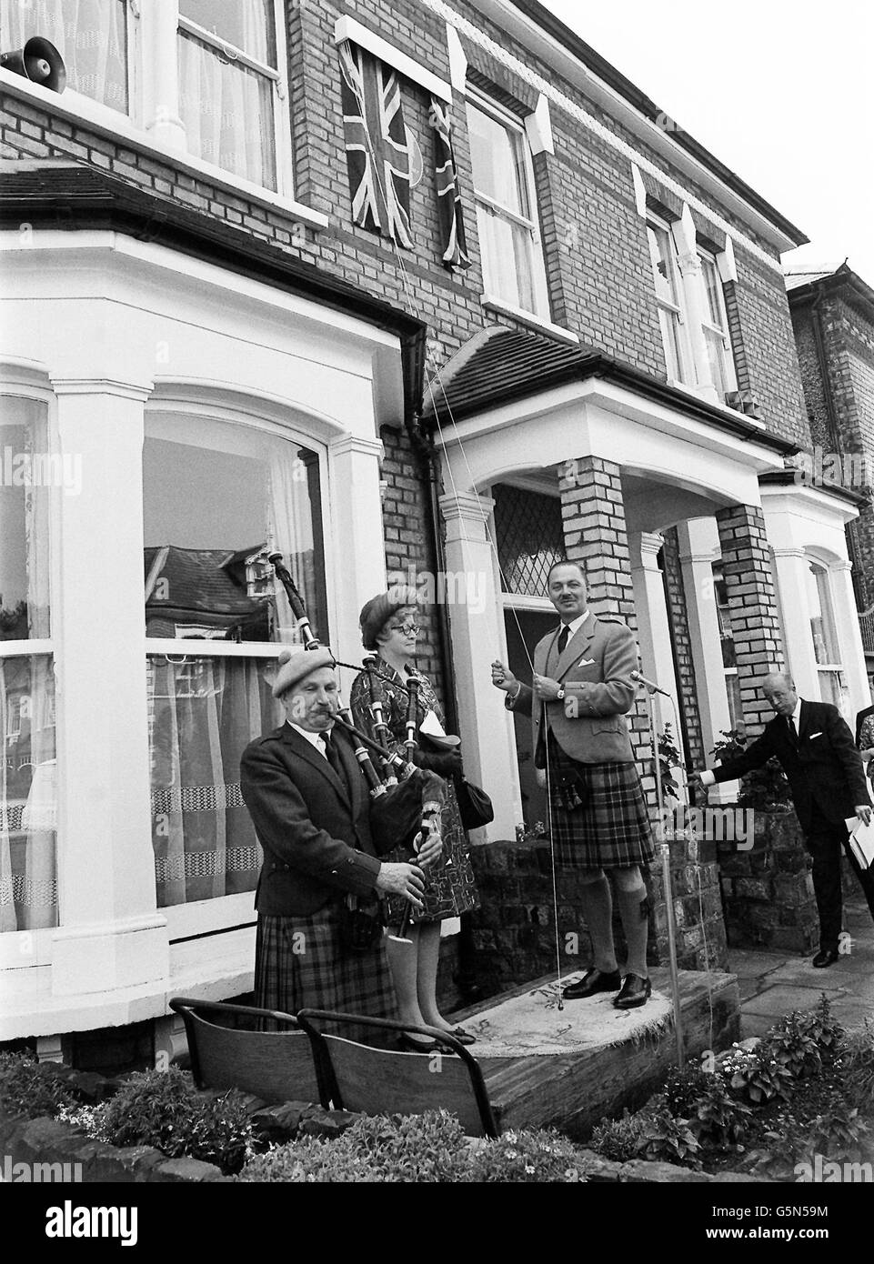To the sound of 'Highland Laddie' played on the pipes by Pipe-MajorIain MacDonald Murray (L) and Kilted Glasgow born Sir Ian MacTaggart (C) unveils a Greater London Council commemorative plaque to Sir Harry Lauder of 1870 - 1950, the famous music hall comedian at 46 Laongley Road, Wandsworth. Stock Photo