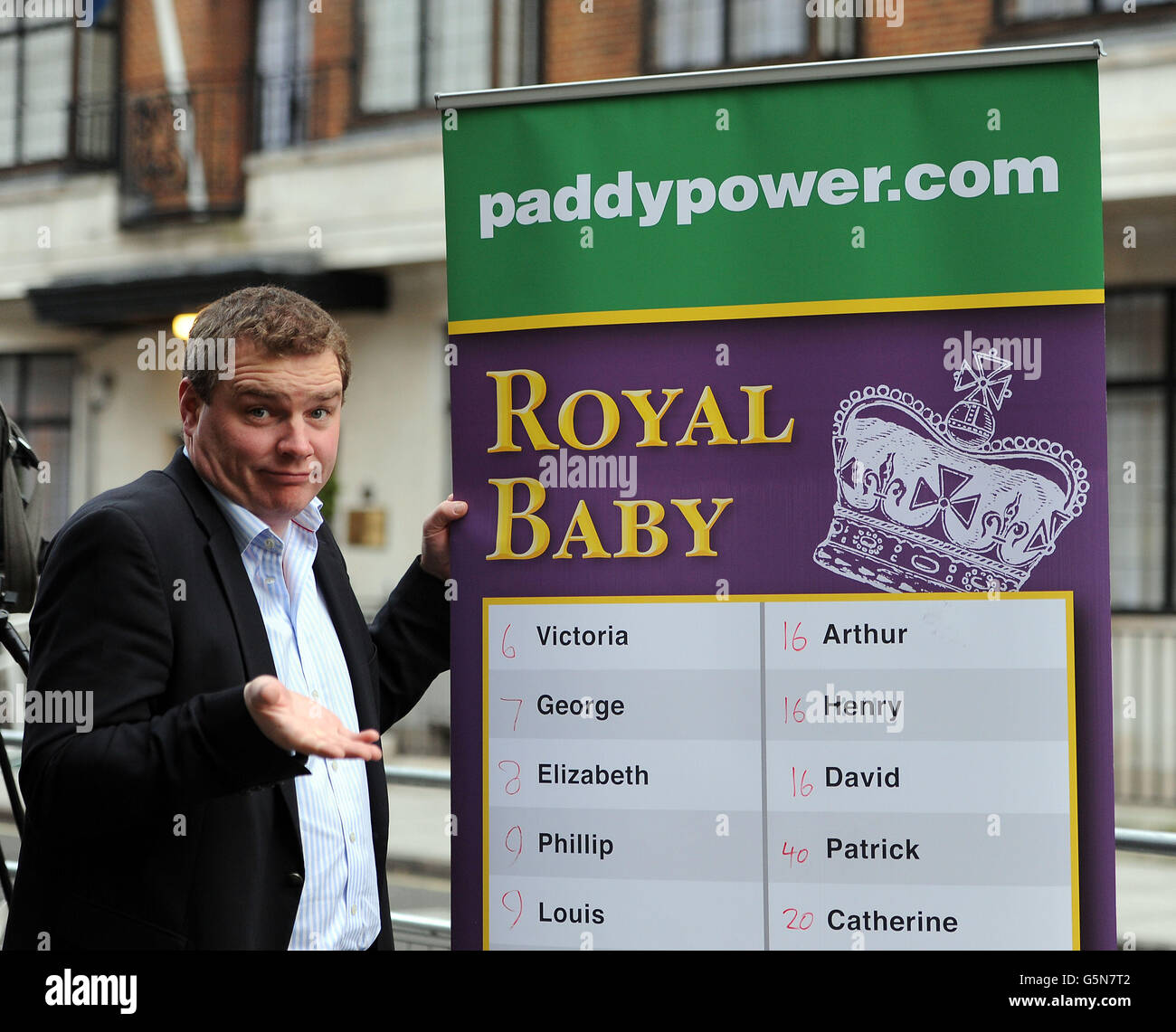 Paddy Power poses with a board of Royal baby names and their odds outside the King Edward VII hospital in London where the Duchess of Cambridge has been admitted with severe morning sickness. Stock Photo