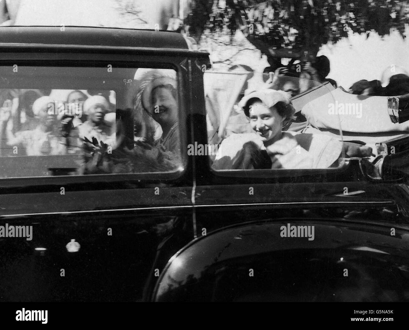 Queen Elizabeth The Queen Mother (L) with her daughter Princess Margaret watch, as they drive in the Royal car, at an dance from African women during their visit to Southern Rhodesia. Stock Photo