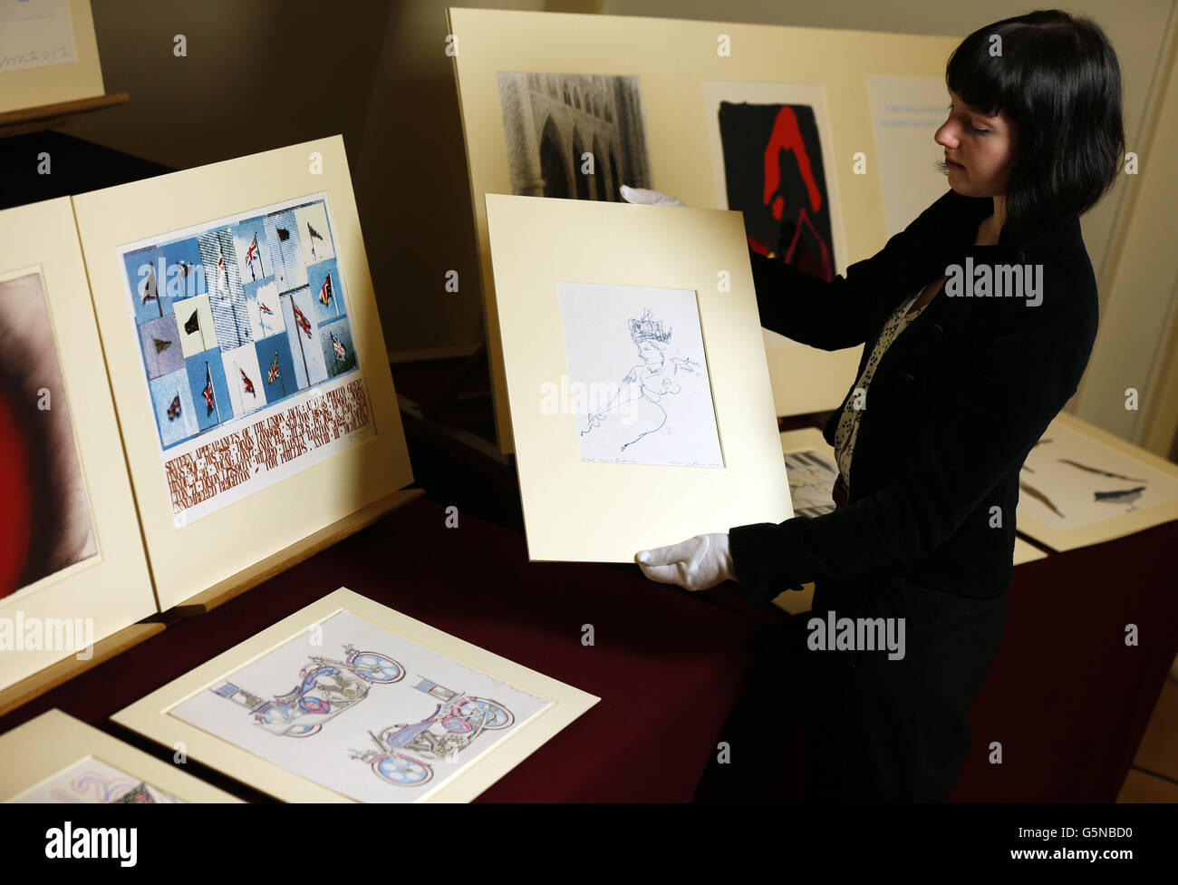 An employee of the Royal Academy of Arts displays 'HRH Royal Britannia 2012' by Tracey Emin, as part of the Diamond Jubilee gift to Queen Elizabeth II, of almost one hundred works of art from the Royal Academy of Arts at the Queen's Gallery, Buckingham Palace. Stock Photo