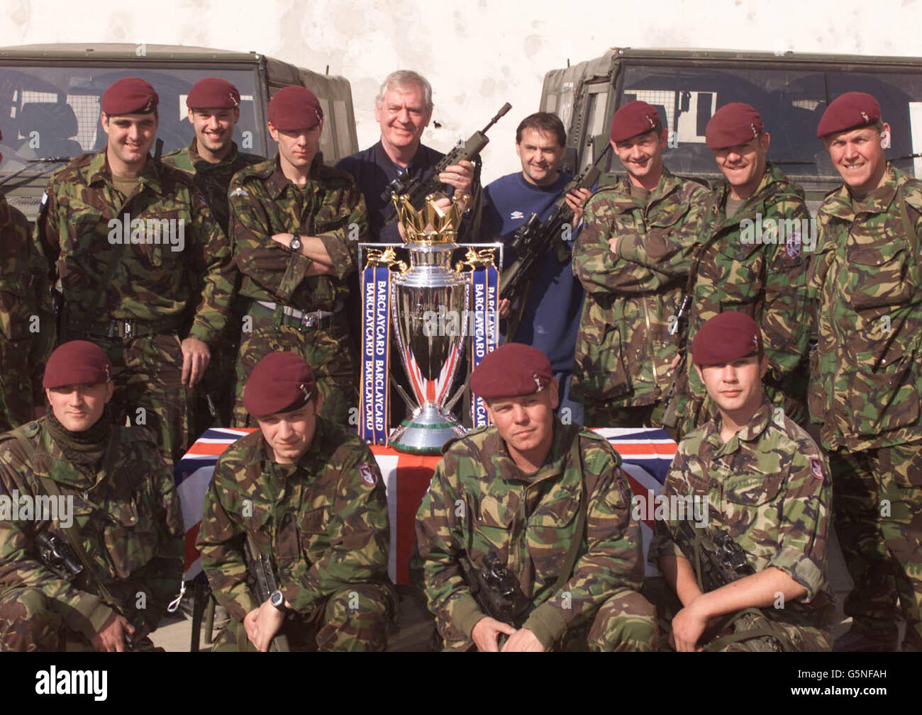 Troops from 216 Royal Signals in Kabul, Afghanistan swap their weapons for the Barclaycard Premiership trophy Wednesday 13th February, 2002. The trophy and Football Association ambasadors Lawrie McMenemy and Gary Mabbutt (centre) * are in the war ravaged country on a morale boosting trip to organise a soccer match between ISAF (International Security Assistance Force) troops and Kabul FC at the Olympic Stadium this Friday, the stadium more infamous for the executions held there by the former Taliban regime than its sporting events. The army team is made up of soldiers from Great Britain, Stock Photo