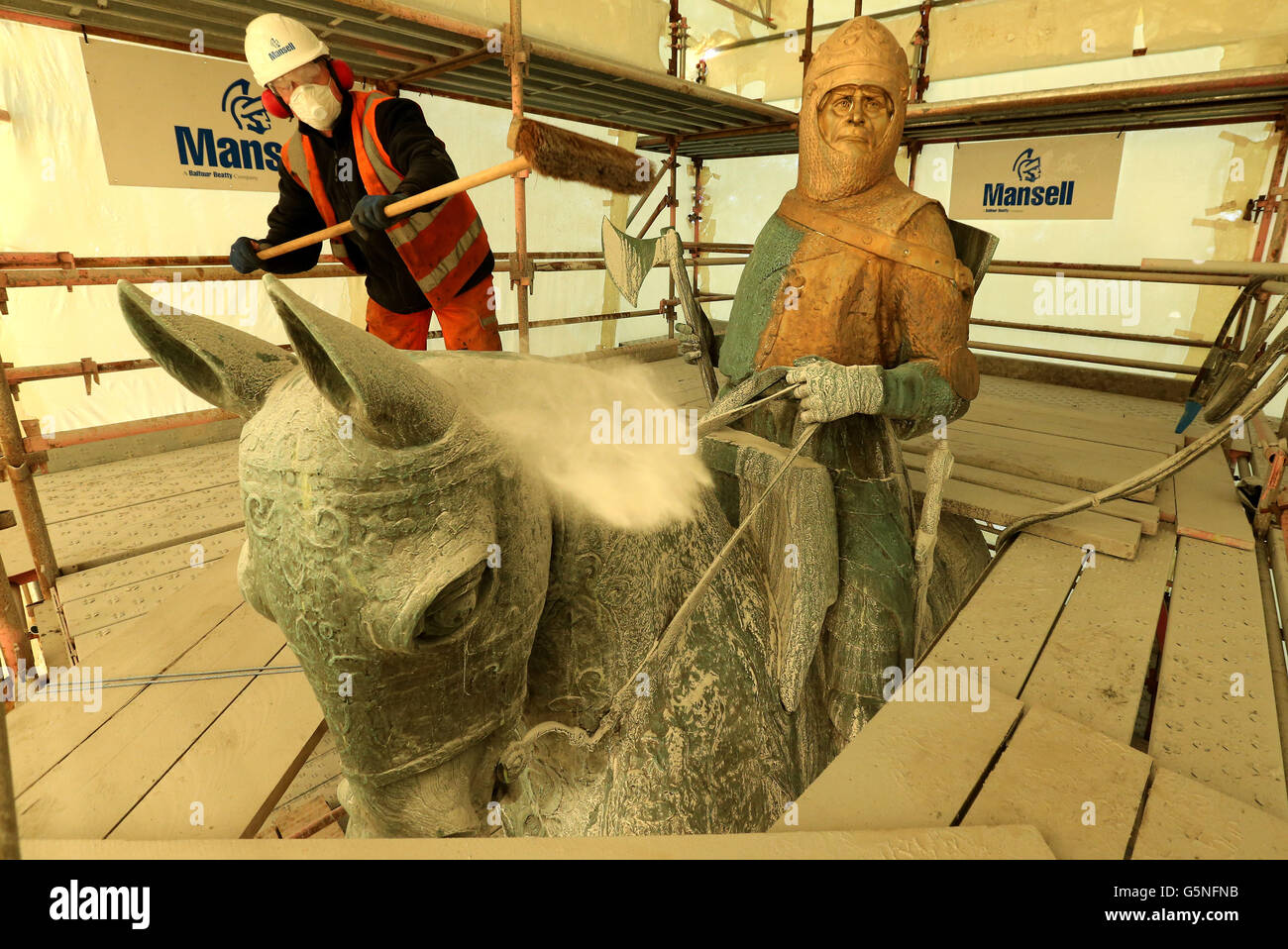 David Oakes from Mansell Construction sweeps dust from the statue of Robert the Bruce during mid restoration work on the weather-beaten statue of Robert the Bruce statue at the Battle of Bannockburn site, ahead of the 700th anniversary of the battle where Bruce is said to have defeated King Edward II's English army to secure an independent monarch for Scotland. Stock Photo