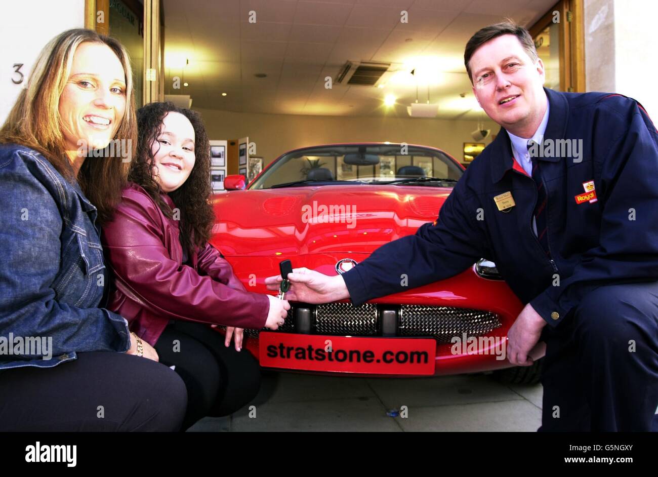 Postman Terry Austen, ands over the keys of a Jaguar XK8 to Kierah Calver, 11, from Ipswich, as her mother Traci looks on, during a photocall at the Jaguar showroom in London's Park Lane. Kierah, won a pair of Jaguar XK8 convertibles, * after winning the Royal Mail's Love Draw competition, in which her card, with a heart drawn on the back of it, was picked at random from over 12 million items of mail. How ever it was mum Traci, who received the two cars because under the stipulation of the terms and conditions of the Love Draw, Kierah was too young to win. Stock Photo