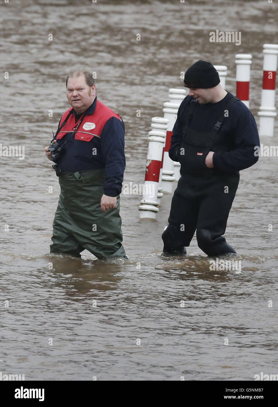 Men walk through flood water in Cupar, Scotland, after the River Eden burst its banks after continued heavy rain. Stock Photo