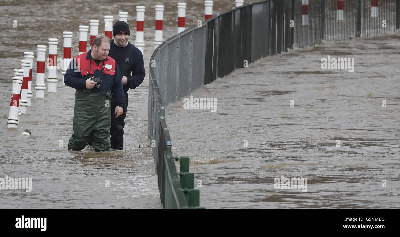 Men walk through flood water in Cupar, Scotland, after the River Eden burst its banks after continued heavy rain. Stock Photo