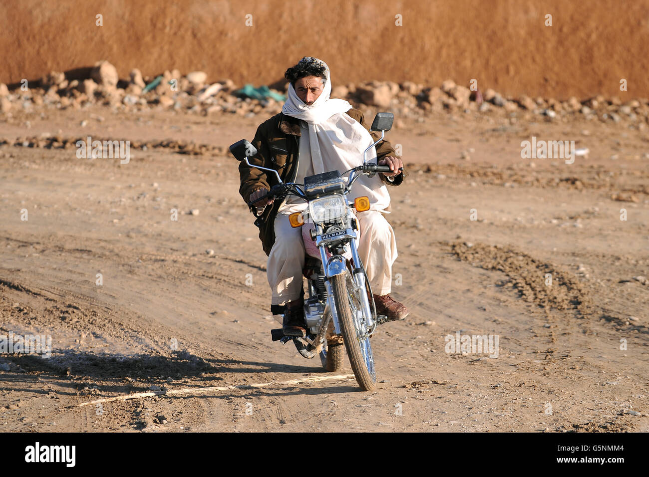 An Afghan local rides his motorbike past checkpoint Chara-He in Helmand Province, Afghanistan Stock Photo