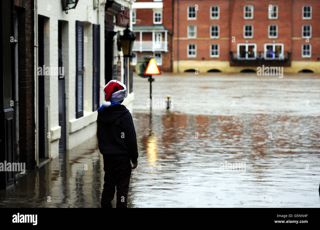 A young Christmas shopper looks at flood water in York city centre as heavy rain continues to cause problems across the UK. Stock Photo