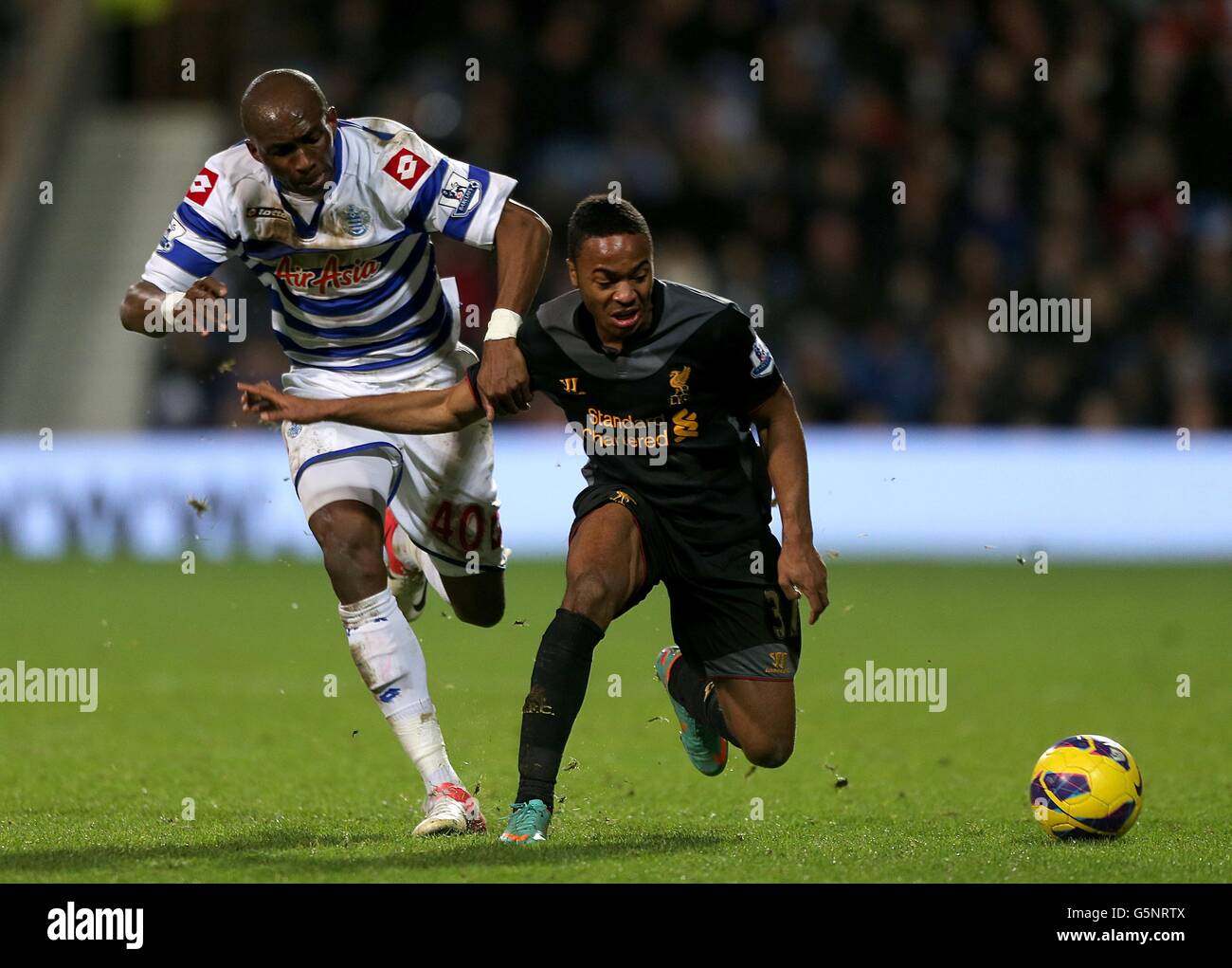Soccer - Barclays Premier League - Queens Park Rangers v Liverpool - Loftus Road. Queens Park Rangers' Stephane Mbia (left) and Liverpool's Raheem Sterling battle for the ball Stock Photo