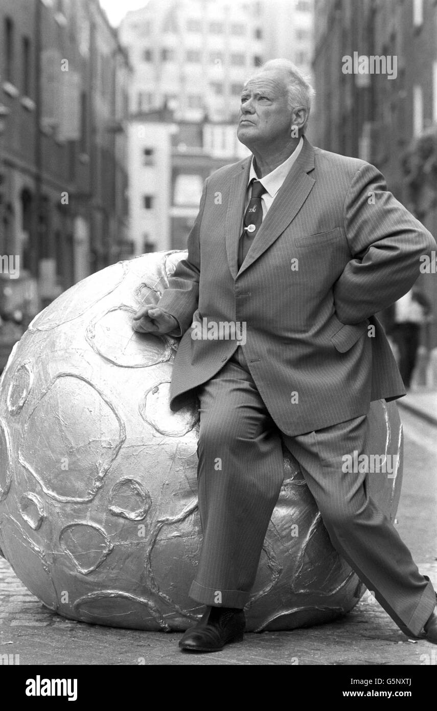 Astronomer Patrick Moore poses with an inflatable asteroid outside the Cambridge Theatre in London's West End, where he will be performing in the sci-fi musical Return to the Forbidden Planet. Stock Photo