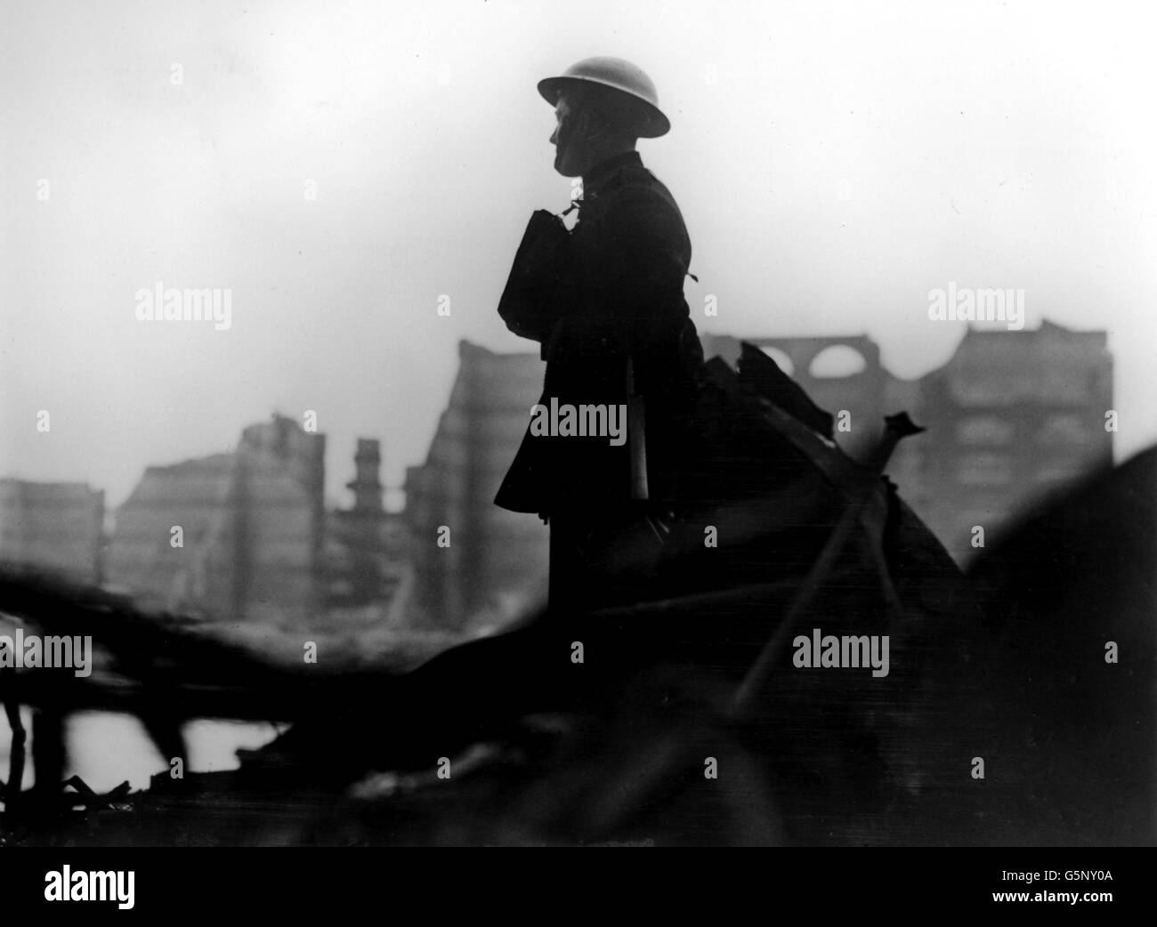 A London fireman gazes out across the devastation caused by Luftwaffe bombing in the docklands area of East London. Ruined warehousing can be seen in the background. Stock Photo