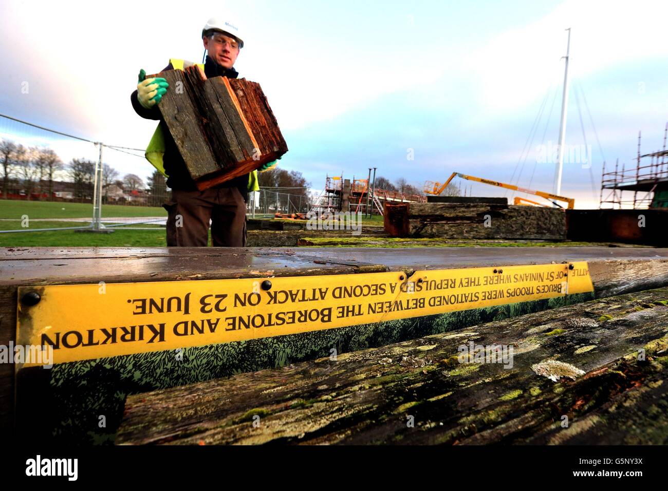 Mike Reid carries an old piece of timber ring beam which has been removed from the 1960s Rotunda Monument at the Battle of Bannockburn, the Heritage site in Bannockburn. A new poem commemorating the site of the Battle of Bannockburn by Scottish poet, essayist and travel writer Kathleen Jamie was announced today. The work will be inscribed on a new timber ring which will crown the Rotunda Monument. Stock Photo