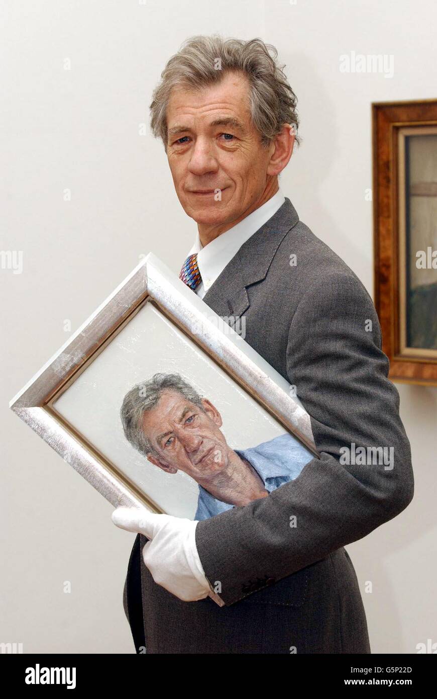 British actor Sir Ian McKellen with a new portrait of himself by Clive Smith during a photocall at the National Portrait Gallery in London. The work will go on public display from Wednesday 27 February 2002. The work has been commissioned by the National Portrait Gallery, * from the artist, who is a previous winner of the BP Portrait Award, as part of this prize. Stock Photo