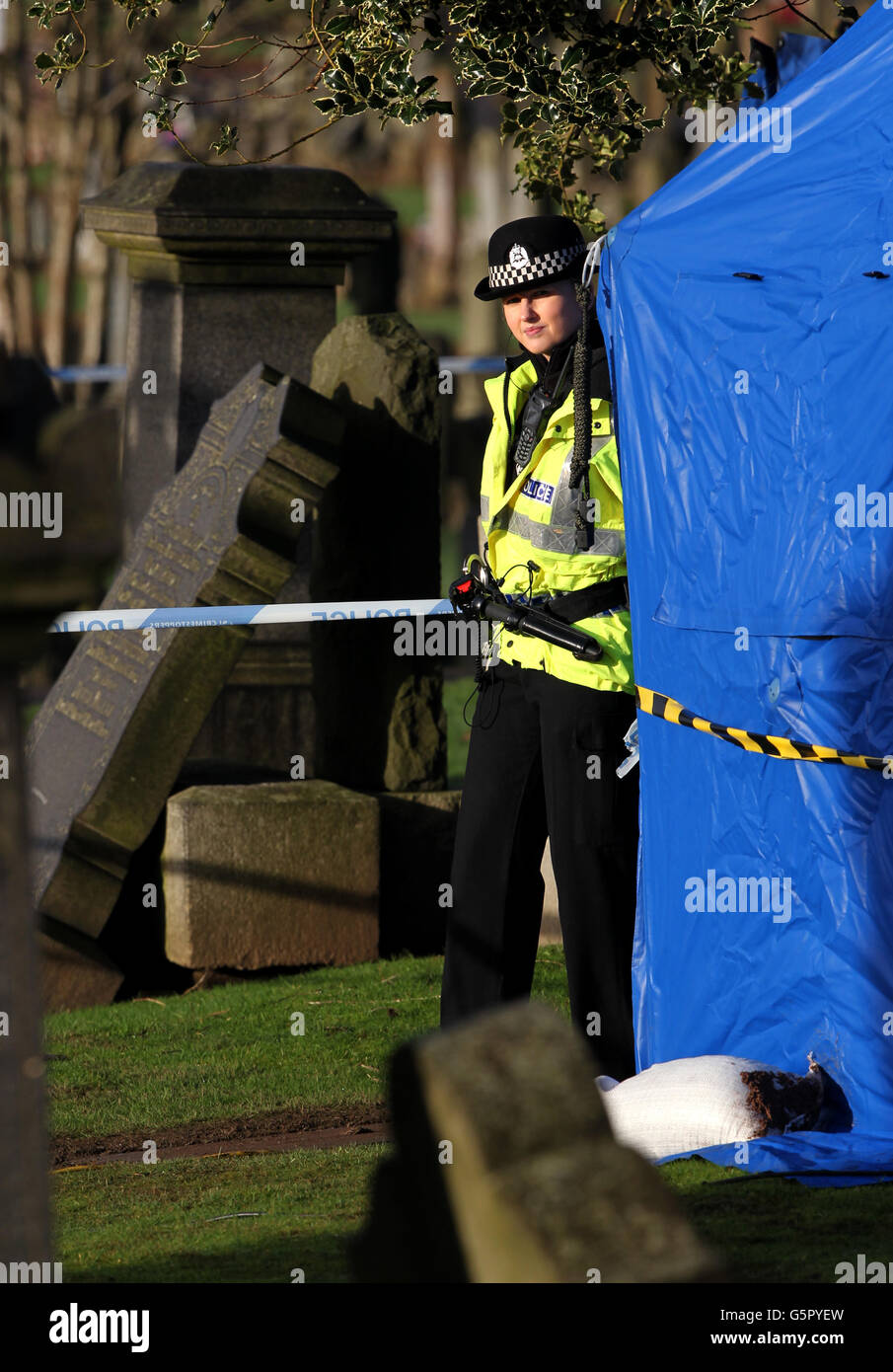 A police woman stands guard at the gravesite at Old Monkland Cemetery in Coatbridge, Scotland where police have started an exhumation of a gravesite in the search for the remains of a schoolgirl Moira Anderson. Stock Photo