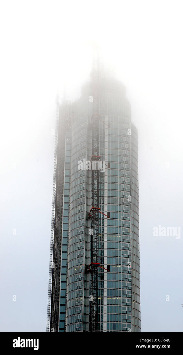 The heavy mist covers the crane at the top of St George's Wharf tower building, where a Helicopter crashed into this morning, in Vauxhall south London. Stock Photo