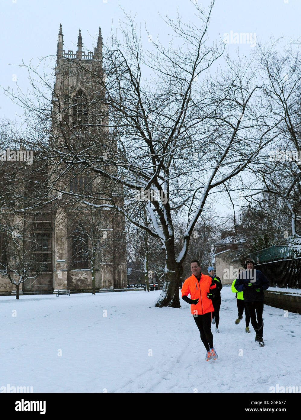 Joggers run along a snow covered path outside York Minster after