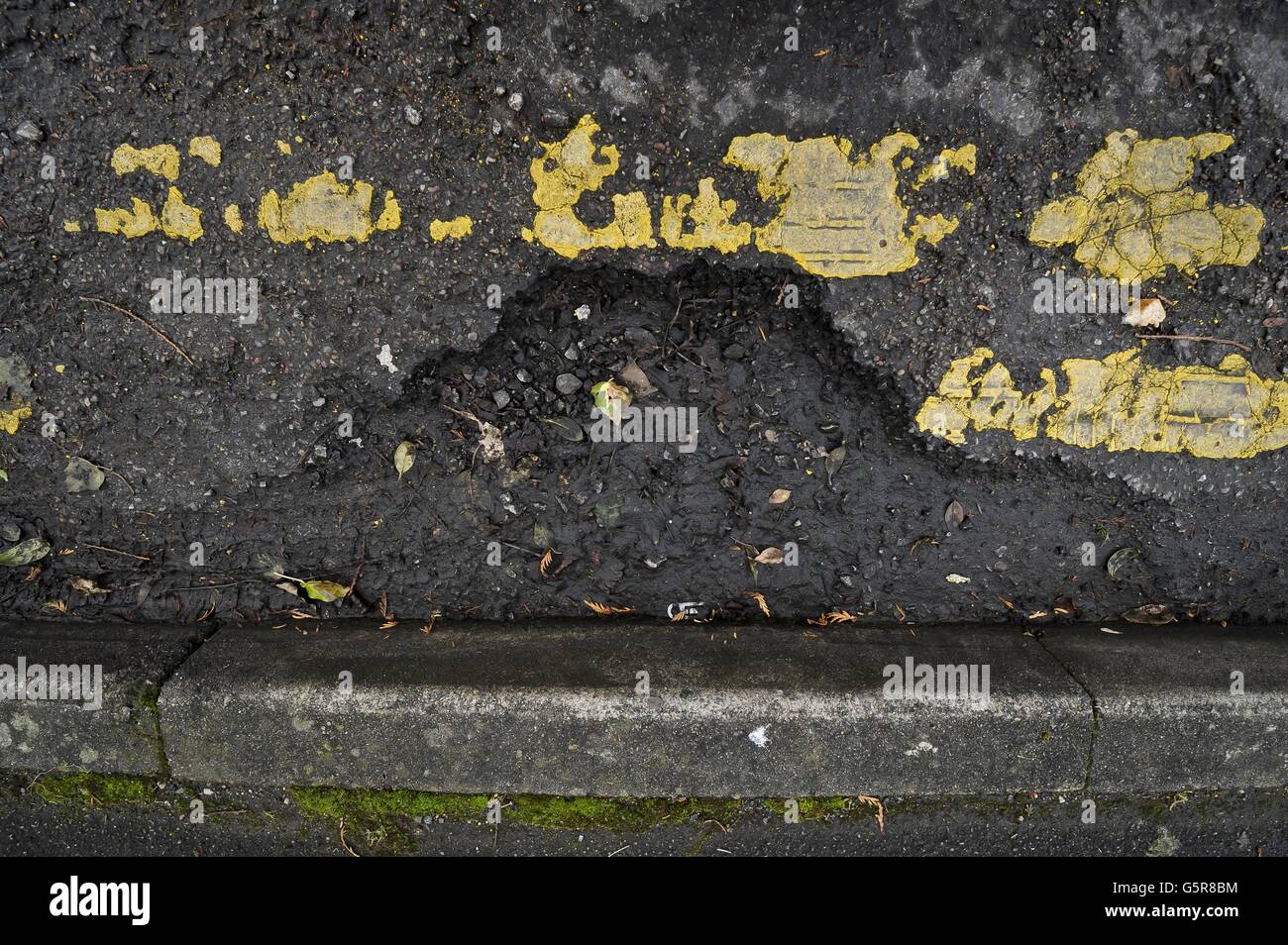 Yellow lines and a crumbling road surface near Gloucester city centre as many roads in the South West are in need of repair and resurfacing work after a year of heavy rainfall and recent flooding, creating potholes and debris. Stock Photo