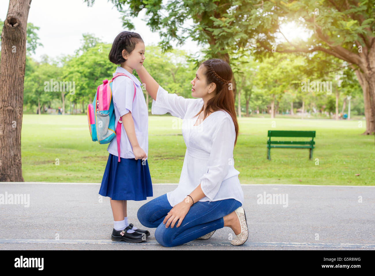 Back to school. Happy Asian mother with kids student in school. Asian mother adjusting kids student shirt in school. Stock Photo