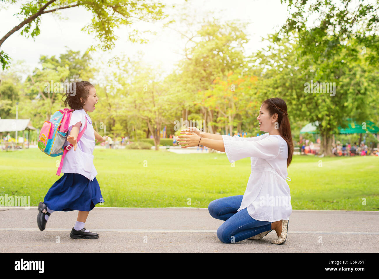 Family, Kids and Mother - Kids student running into mother's hands to hug her. Family having fun in the park. Kids is happy to m Stock Photo