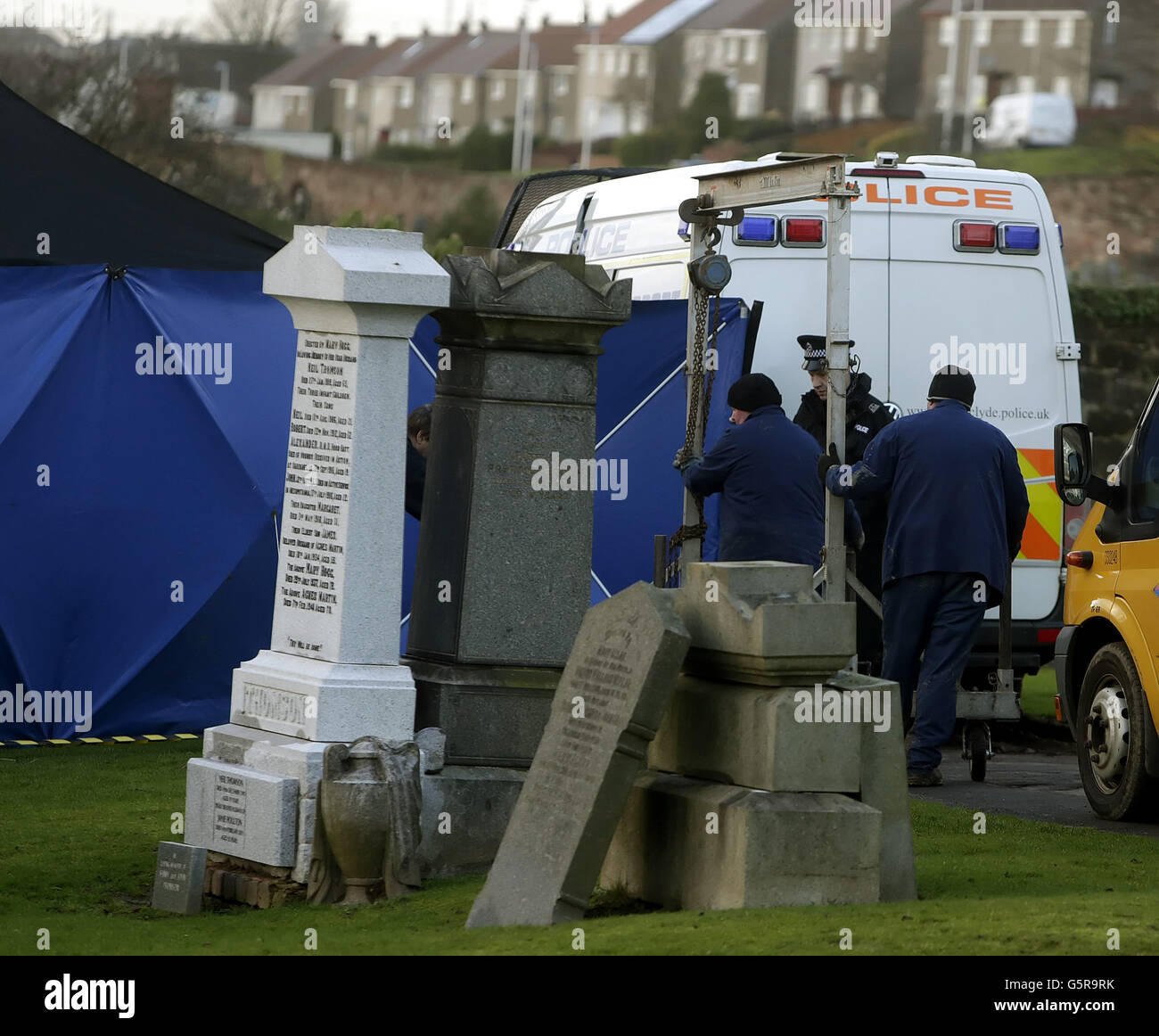 A crane is moved behind a police screen at Old Monkland Cemetery in Coatbridge in Scotland where an exhumation of the gravesite in the search for the remains of a schoolgirl Moira Anderson began today. Stock Photo