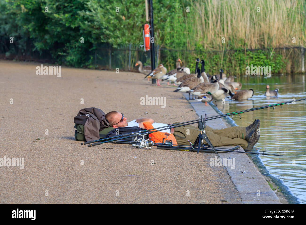 Yong man a sleep by the serpentine Lake while fishing in Hyde park