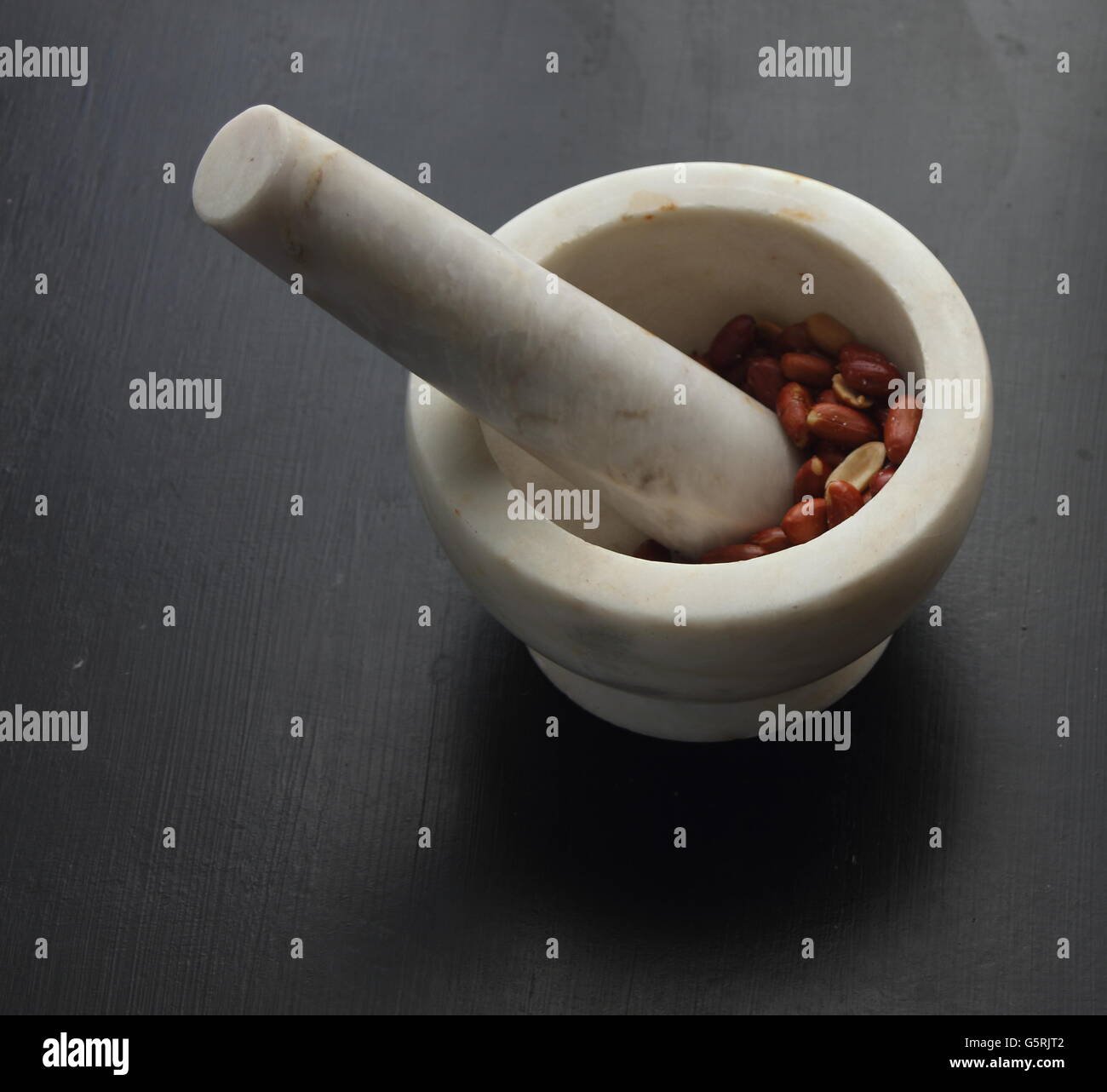 Peanuts about to be crushed by a mortar and pestle Stock Photo