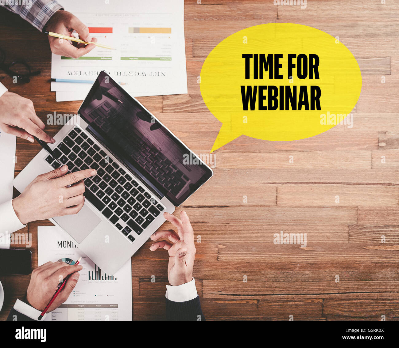 BUSINESS TEAM WORKING IN OFFICE WITH TIME FOR WEBINAR SPEECH BUBBLE ON DESK Stock Photo