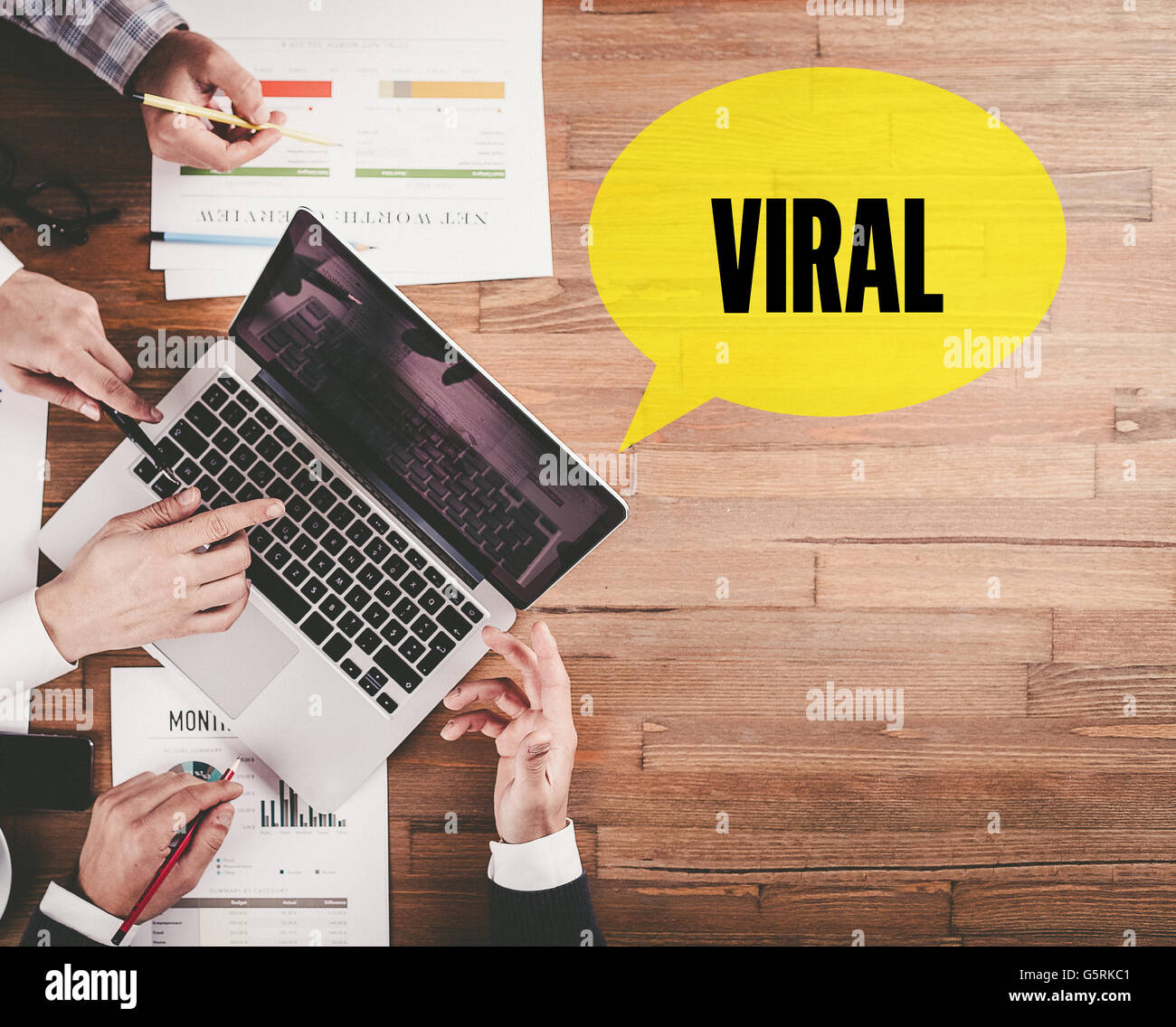 BUSINESS TEAM WORKING IN OFFICE WITH VIRAL SPEECH BUBBLE ON DESK Stock Photo