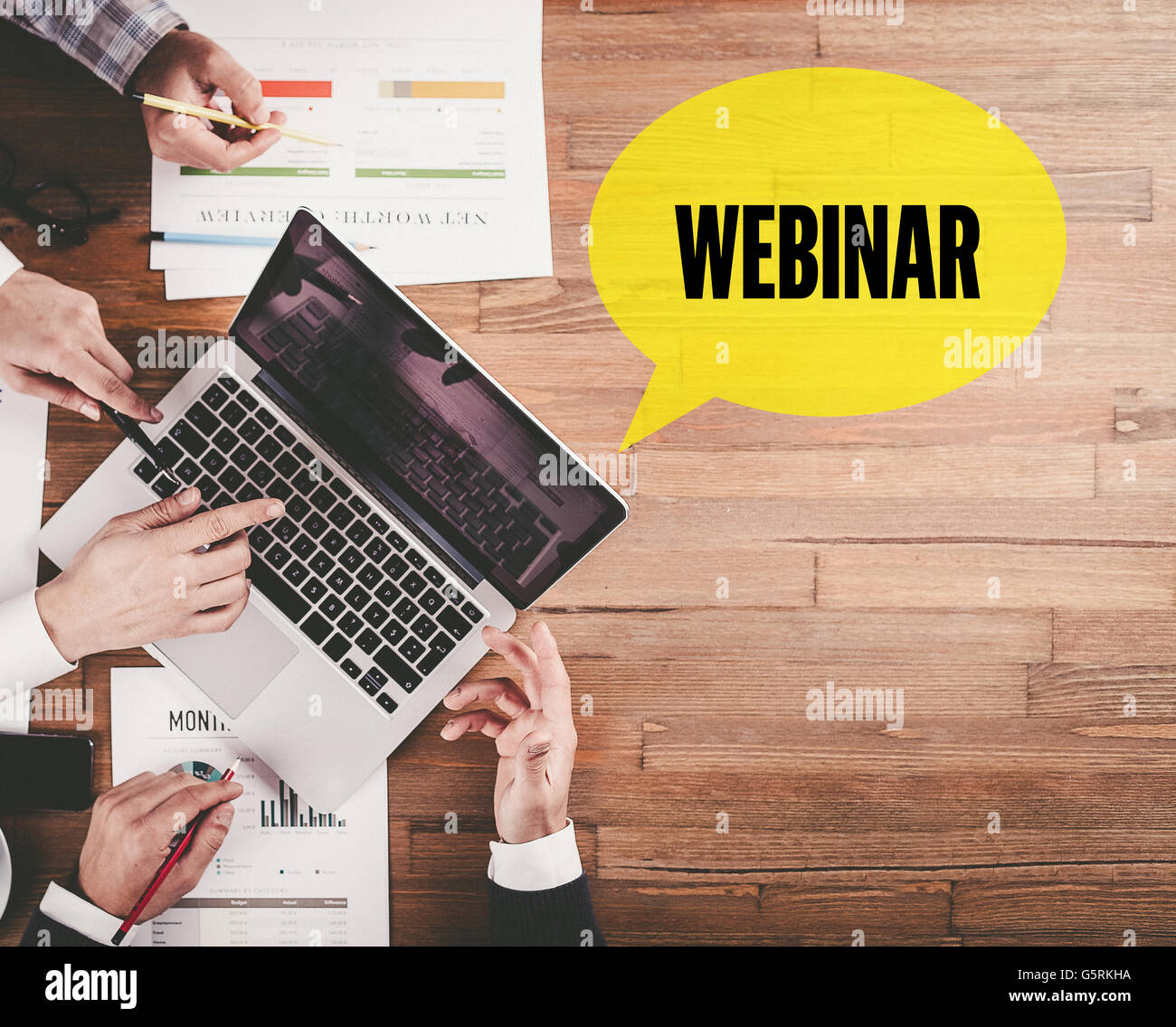BUSINESS TEAM WORKING IN OFFICE WITH WEBINAR SPEECH BUBBLE ON DESK Stock Photo