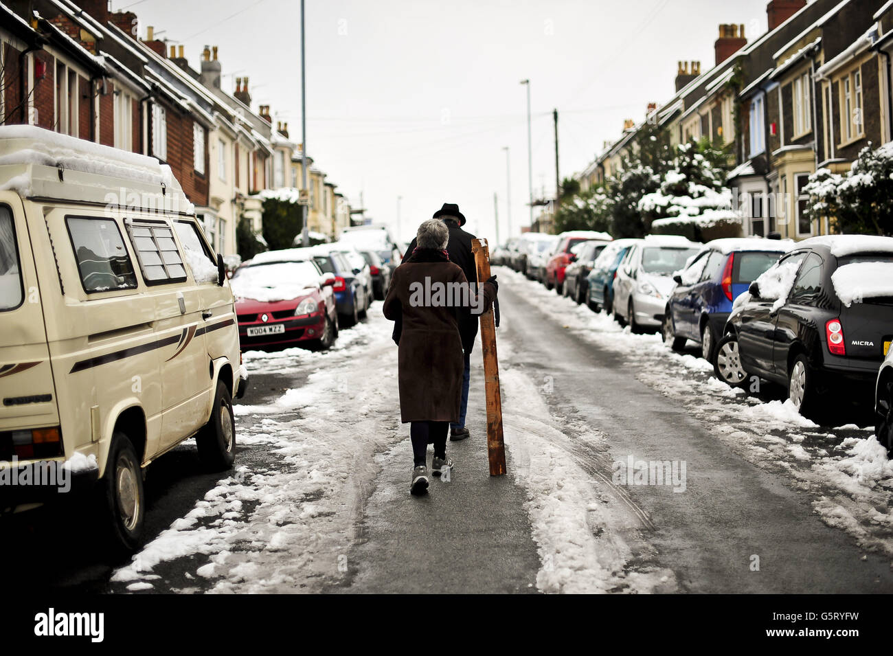 A woman walks in the road with a plank of wood as most paths around Bristol are covered in compact snow and ice. Stock Photo