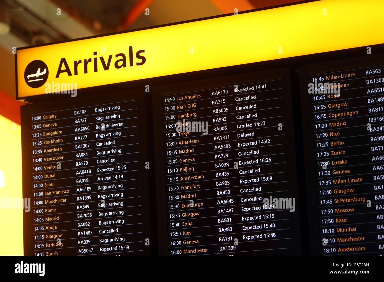 An Arrivals Board at Heathrow Airport showing delayed an cancelled flights as the winter weather continues across the UK. Stock Photo