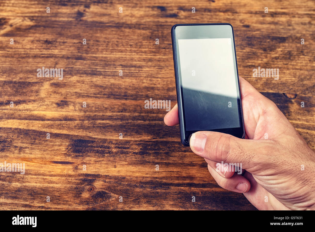 Male hand using smart phone over wooden office desk with copy space Stock Photo