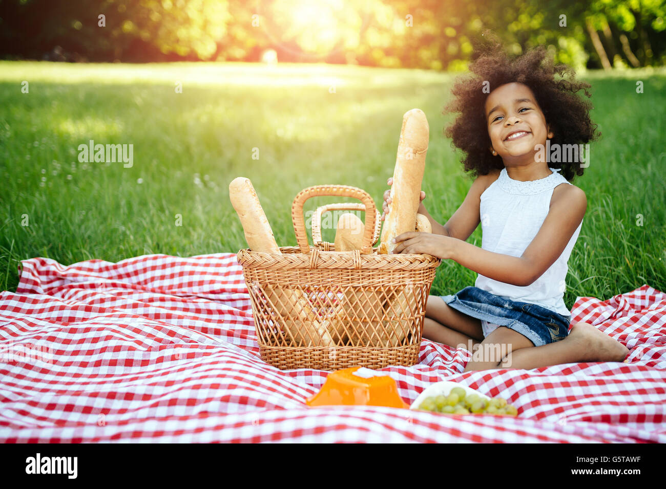 Beautiful afro kid holding baguette while picnicking Stock Photo
