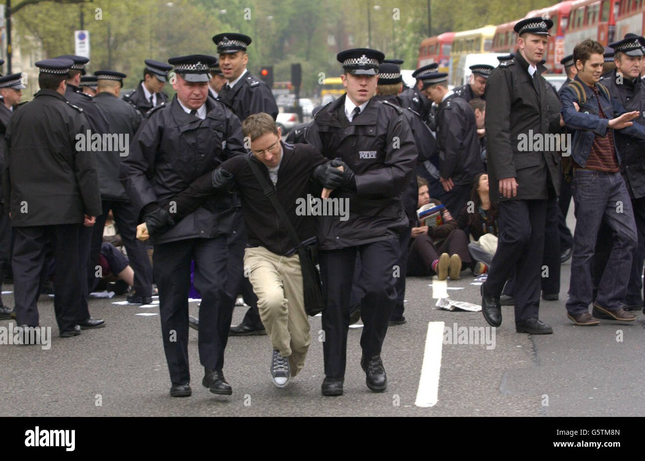 An activist from the Get Kissinger Group is led away by police whilst protesting against the arrival of Henry Kissinger, the former United States Secretary of State, who is to speak at an Institute of Directors meeting at the Royal Albert Hall in London. *Human rights campaigners and a group of leftwing Labour MPs have accused Dr Kissinger of aiding and abetting war crimes in Vietnam, Laos and Cambodia when he was in office. The theme of the conference, globalisation, was also expected to spark protests from anti-globalisation campaigners. Stock Photo