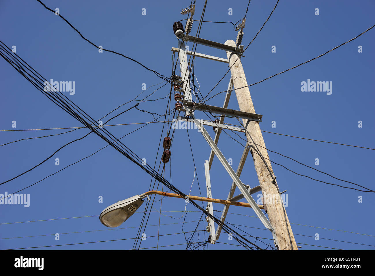 Old fashion power pole with many wires against the blue sky Stock Photo