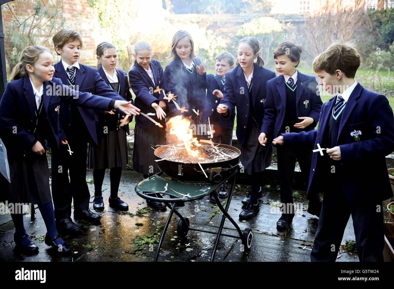 Young trainee choristers, known as a probationers, of Salisbury Cathedral choir burn Palm crosses as they celebrate and learn about Shrove Tuesday a week early as they will be on half-term on pancake day. Stock Photo