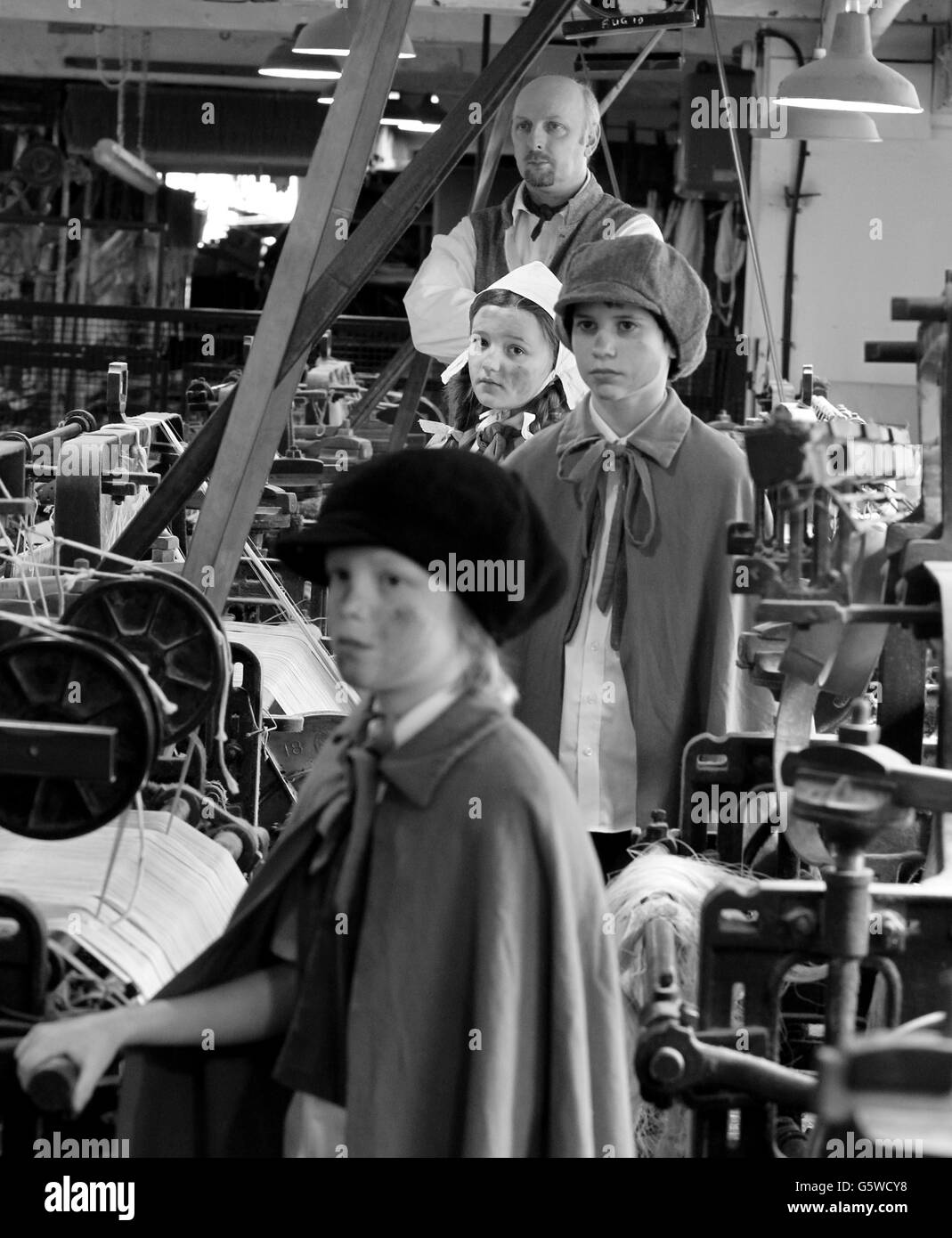 COLOUR IMAGES CONVERTED INTO BLACK AND WHITE. Children from Style Primary School part of the Quarry Bank Mill Estate re-inact a workforce at the Quarry Bank Mill, which is owned by The National Trust. Stock Photo