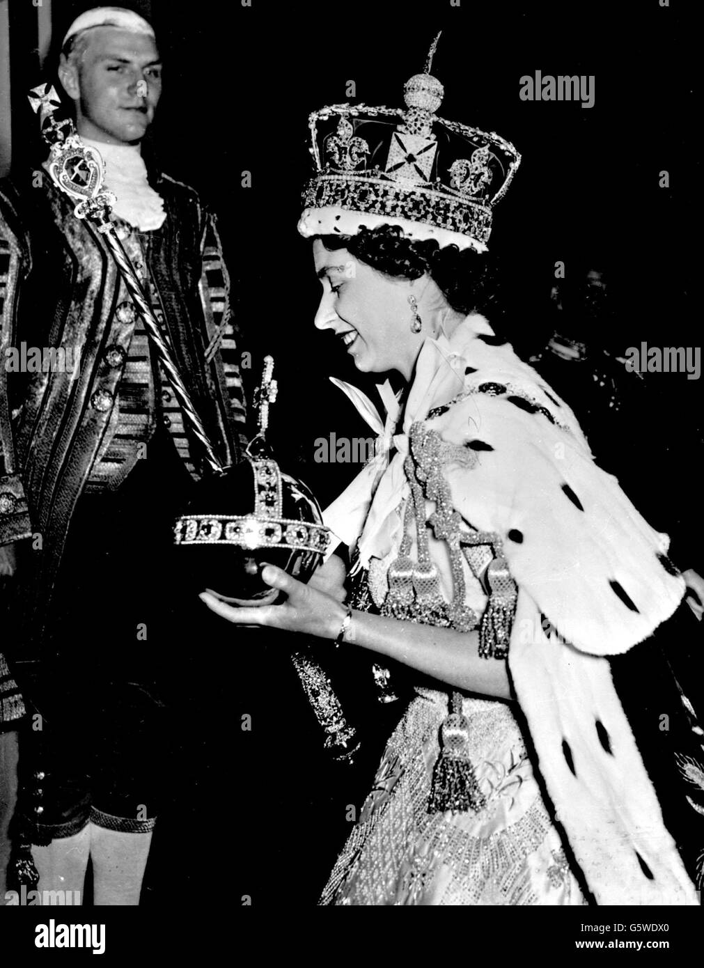 The smiling Queen Elizabeth II wearing the Imperial State Crown and carrying the Orb after alighting from the State Coach at Buckingham Palace. Stock Photo