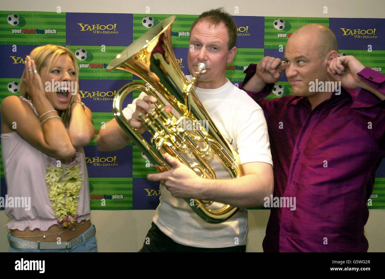 Television presenters Tess Daly and Terry Alderton hold their ears as 38-year-old Steve Wood from Sheffield (centre) plays his euphonium at the London Television Studios. * ...... Steve won a trip to the world cup finals in Japan and South Korea in tonight's 'Yahoo!'s Your World Cup Pitch' television show. Stock Photo
