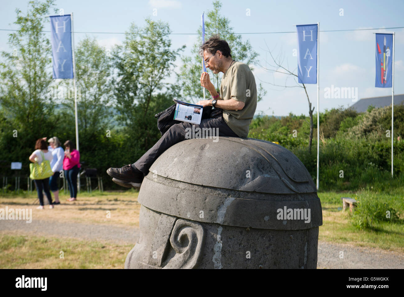 A man sitting on the giant head sculpture enjoying the warm summer