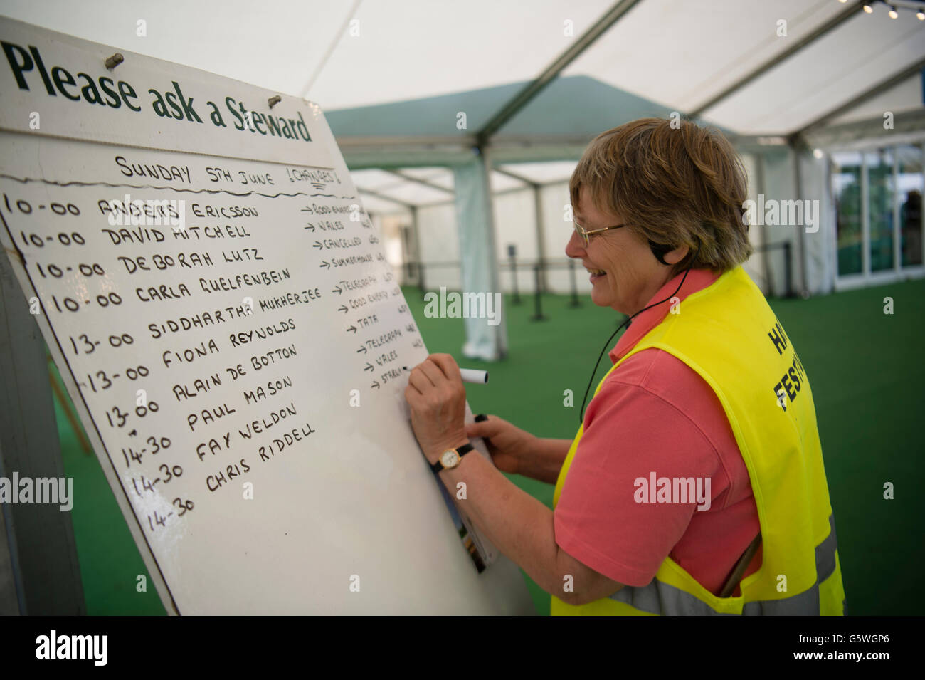 A woman volunteer writing out changes to the events timetable at The Hay Festival of Literature and the Arts, Hay on Wye, Powys, Wales UK, Sunday June 05 2016 Stock Photo